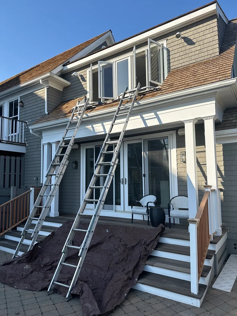 Ladders set up on a wood roof to replace this casement window in Norwalk, CT